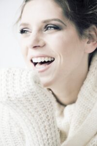 Glückliche Frau lächelt mit gesunden, weißen Zähnen