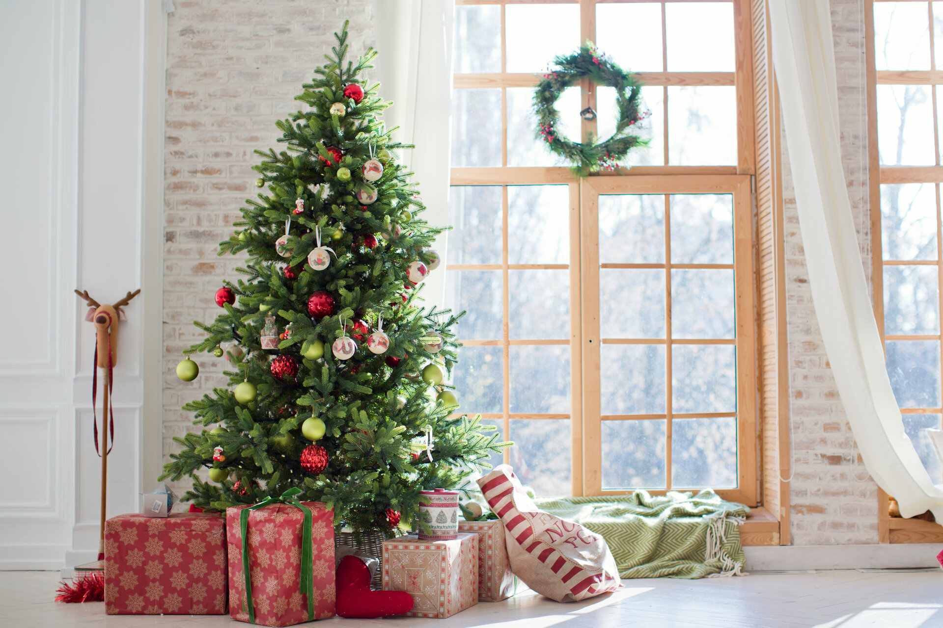Künstlicher Weihnachtsbaum und Geschenkboxen in der Nähe eines Fensters.